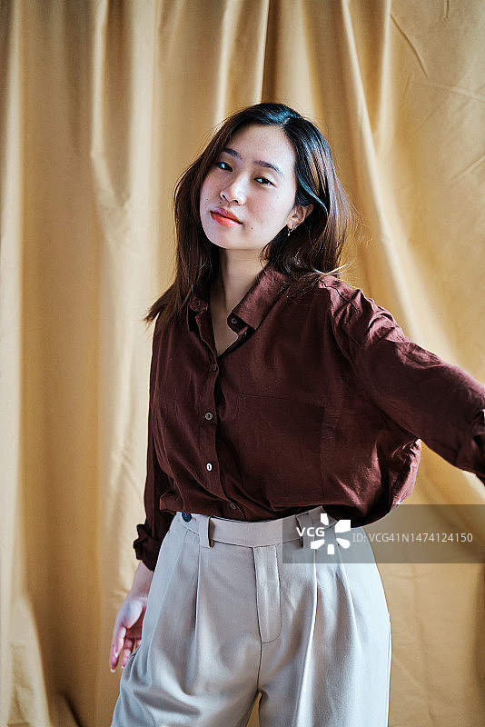 女子站在工作室的窗帘旁图片素材