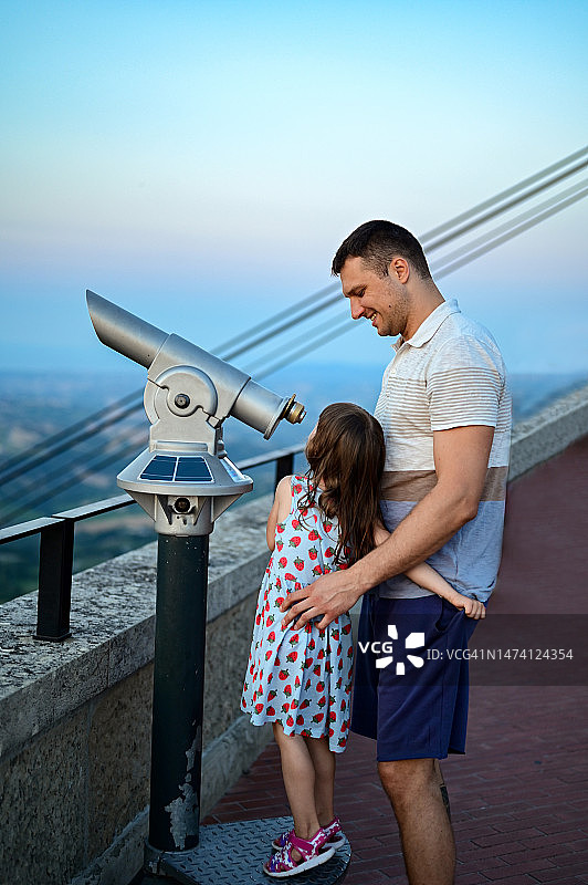 父亲和幼儿女儿拿着望远镜在城市旅行图片素材