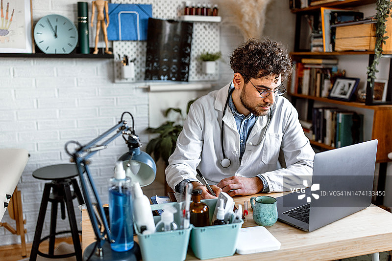 医生在办公室的桌子旁使用笔记本电脑图片素材
