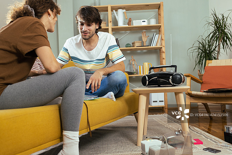 年轻男人和他的女朋友寻找旧音乐CD并享受复古音乐图片素材