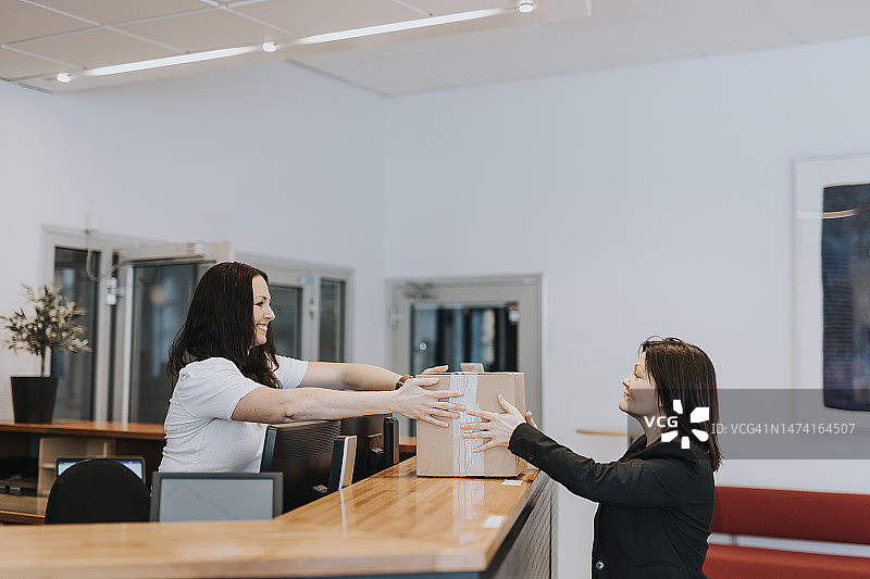 在办公室手拿纸箱的微笑女人图片素材