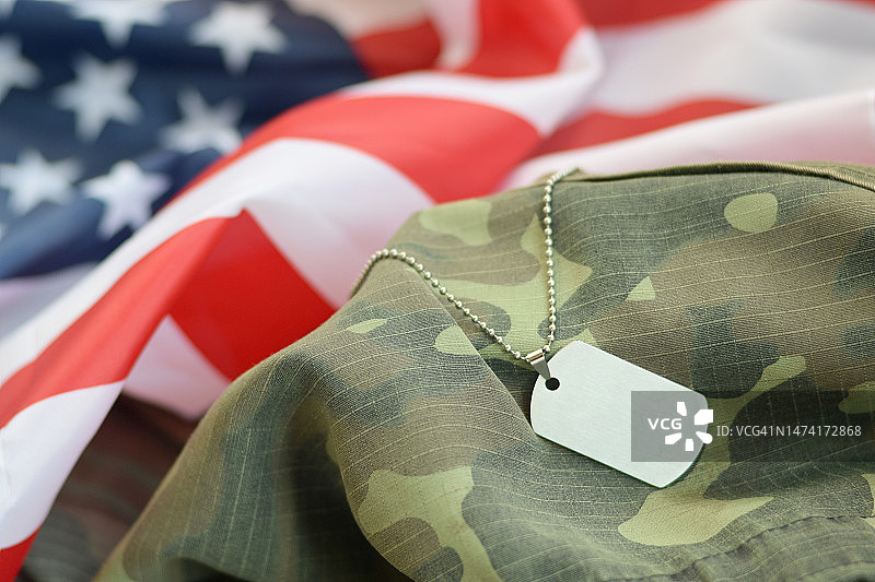 带有狗牌的银色军用珠子，位于美国国旗和罗马尼亚迷彩服上图片素材