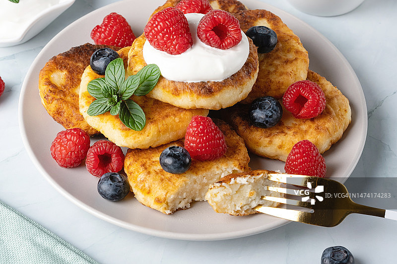 浅色背景下的覆盆子和蓝莓奶酪煎饼，早餐或午餐，俄罗斯斯塔夫罗波尔图片素材