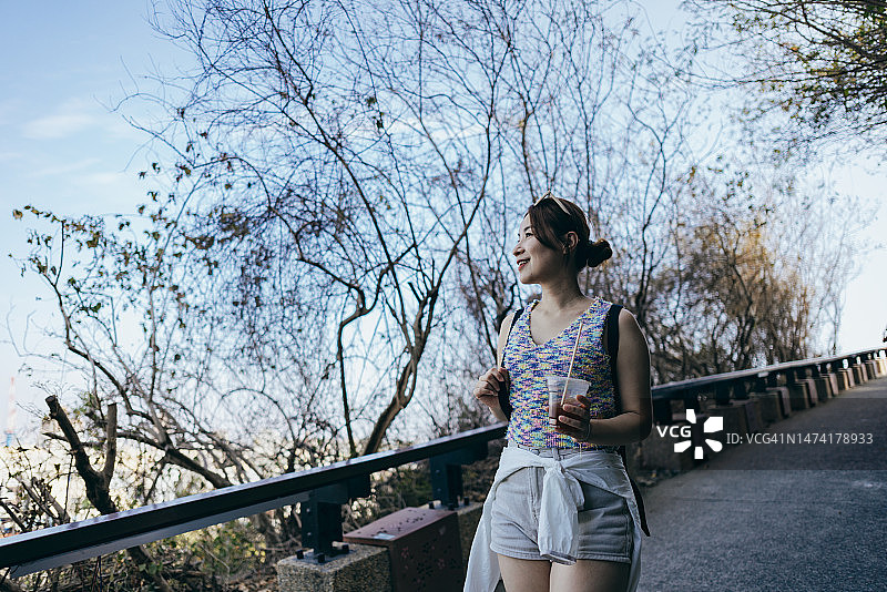 亚洲女人在旅游景点漫步，欣赏美丽的风景，呼吸新鲜空气，享受植物杀菌素释放带来的益处图片素材