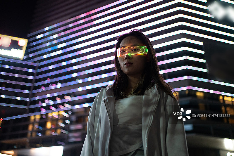 亚洲年轻女子在城市街道上使用VR眼镜图片素材