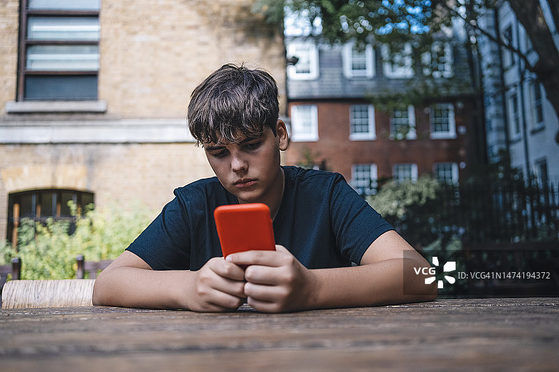 青少年坐在伦敦的公园里使用手机图片素材