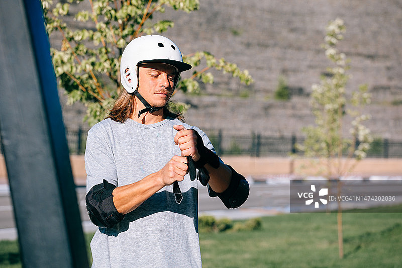 中年男子滑板爱好者准备滑板并戴上防护装备图片素材