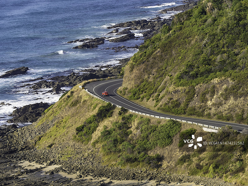 红色汽车行驶在蜿蜒的海边公路上图片素材