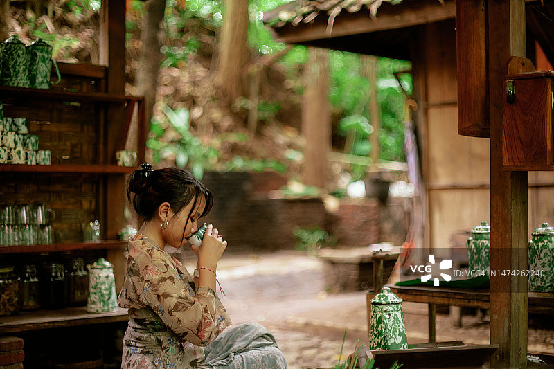 穿着卡巴雅的亚洲女孩在爪哇老式公共厨房喝凉茶图片素材