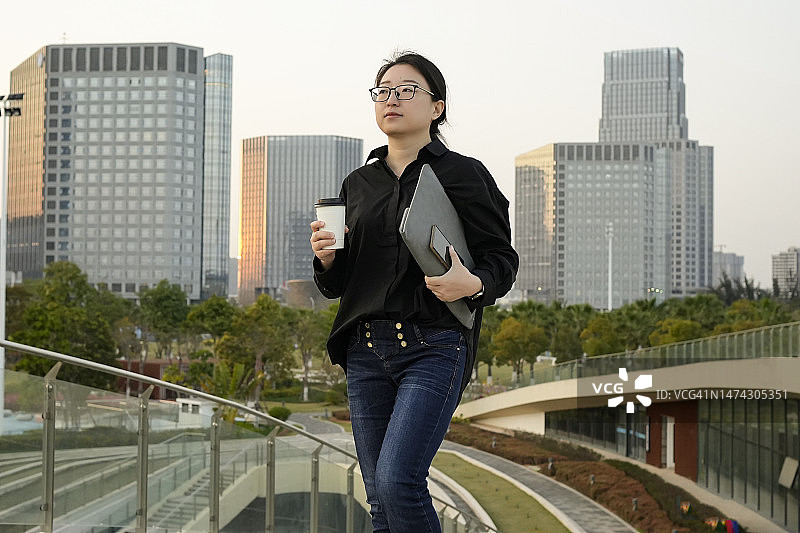 手拿咖啡和手机的商务女性在户外图片素材