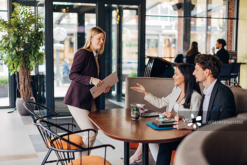 两位商务人士在咖啡店迎接前来面试的女性应聘者图片素材