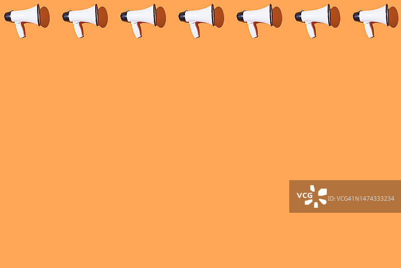 橙色背景上的白色扩音器图案，表达呼喊、消息和新闻概念图片素材