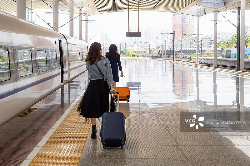两位女士拖着行李箱的背影图片素材