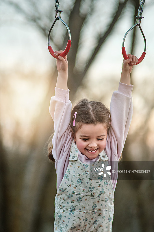 小女孩在公园的吊环上玩耍图片素材