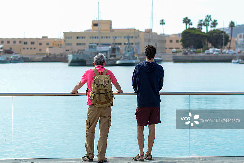 父亲和成年儿子在海边度假图片素材