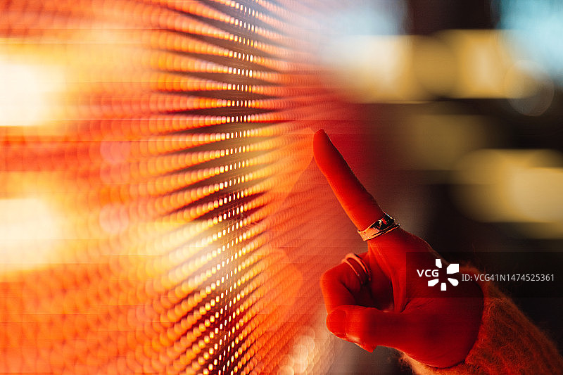 女人触摸发光数字显示屏的手部特写图片素材