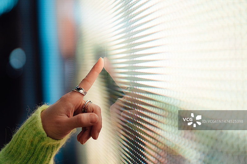 女人触摸发光数字显示屏的手部特写图片素材