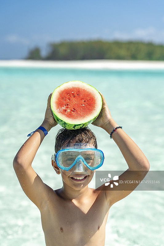 戴着潜水面罩抱着西瓜的可爱男孩图片素材