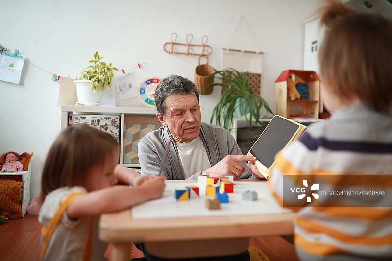 男教师在幼儿园课堂上指着平板电脑屏幕图片素材