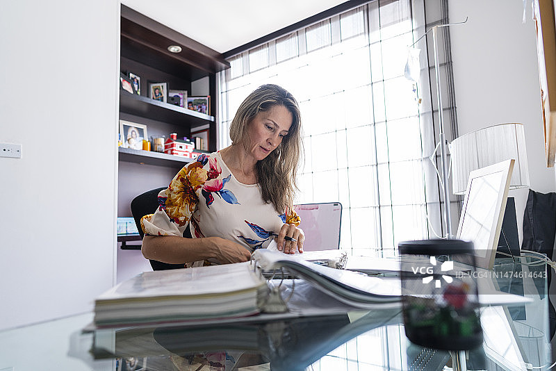 在家办公的拉丁裔女子查阅文件图片素材