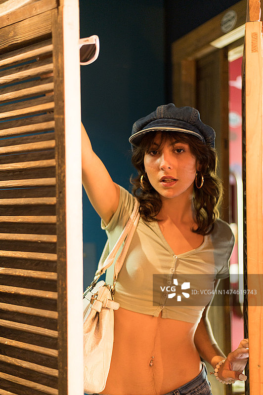 戴帽子的年轻女孩打开木门看向镜头图片素材