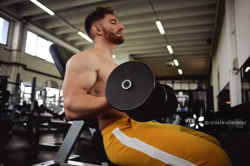 在运动俱乐部用哑铃锻炼的男人侧视图图片素材