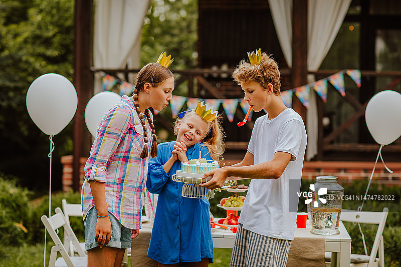 青少年在装饰好的生日桌旁摆姿势吹蜡烛图片素材