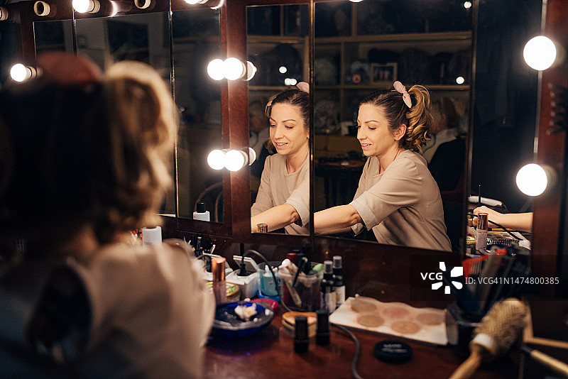 女演员在剧院后台的镜子前化妆图片素材