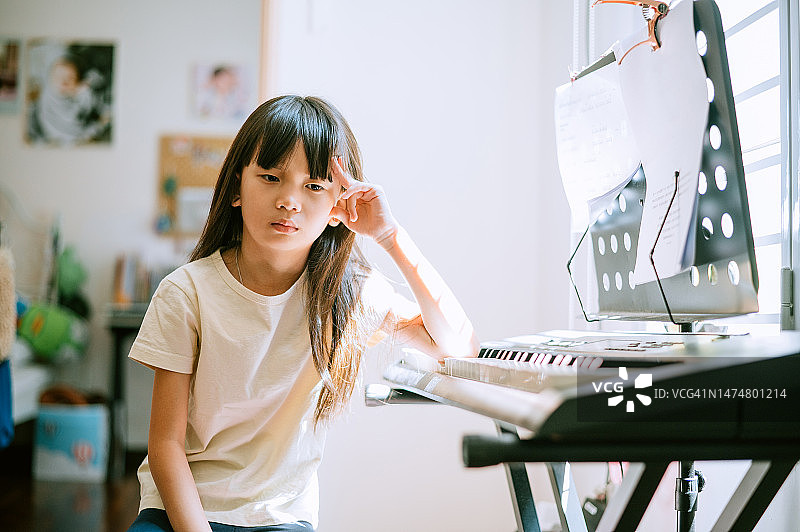 华人小女孩在练习电子琴时感到不舒服图片素材