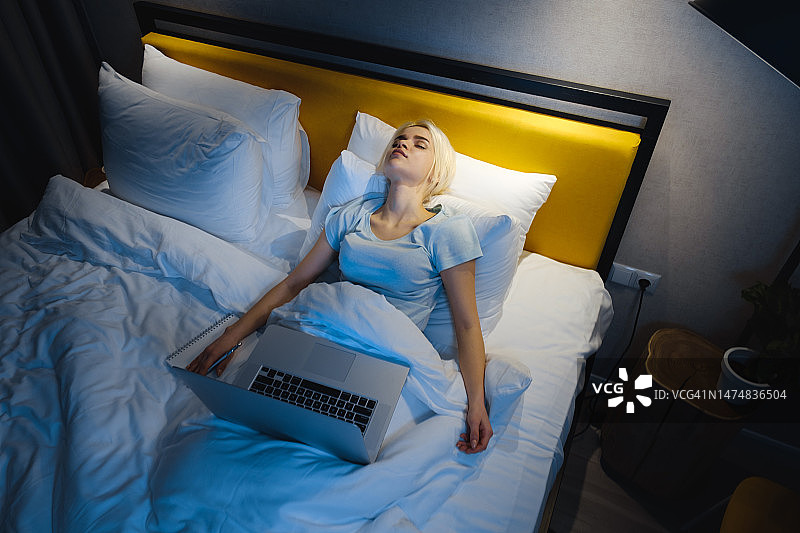疲惫的女人在笔记本电脑上看视频时睡着了图片素材