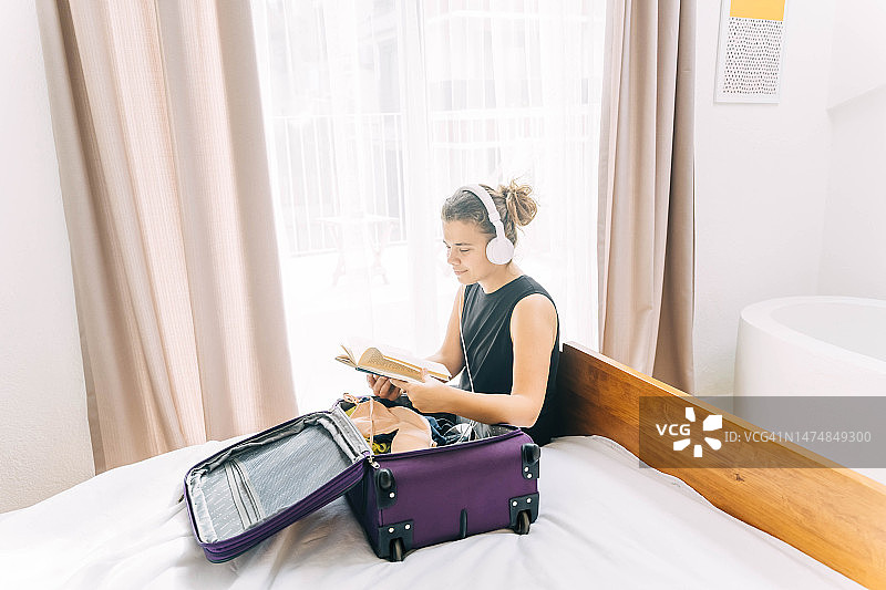 中年女人入住酒店并打开行李箱整理物品。图片素材