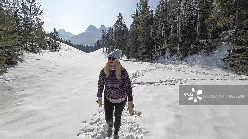 中年妇女在森林雪地小路上行走图片素材