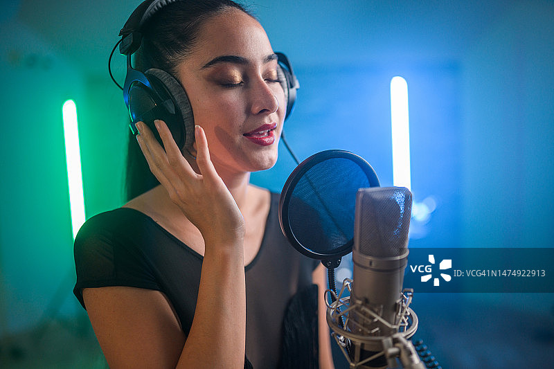 年轻美丽的亚洲女人在录音室唱歌图片素材
