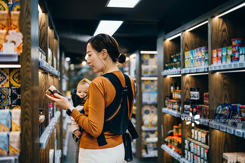 年轻的亚洲母亲带女儿在超市购买有机蜂蜜图片素材