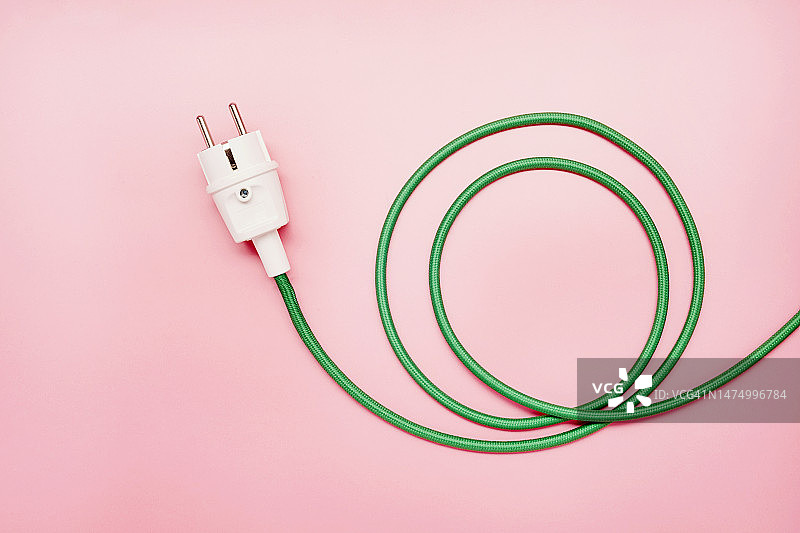 粉色背景上的绿色电源线和插头图片素材