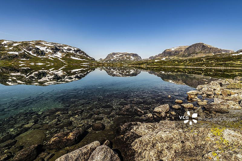 挪威哈当厄尔高原，豪克利山，斯塔瓦特恩湖中积雪山脉倒影图片素材