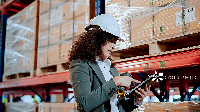 贸易公司的年轻亚洲员工在仓库中使用平板电脑和条形码扫描器进行库存盘点图片素材