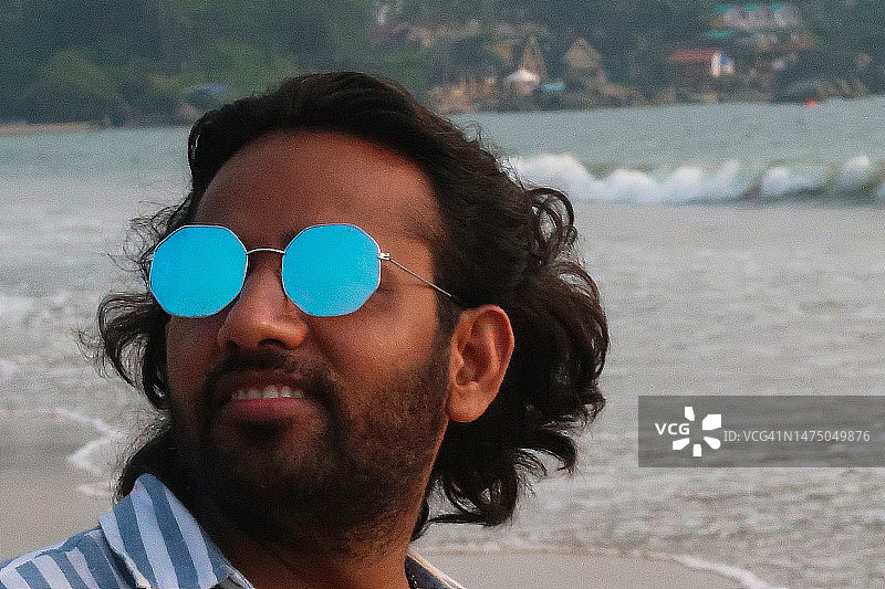 印度果阿海滩度假男子特写，佩戴反光太阳镜图片素材