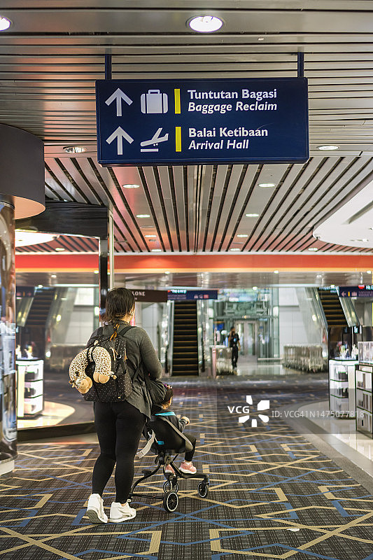 在马来西亚机场，母亲推着载有幼儿的婴儿车图片素材