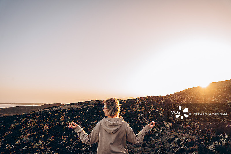 年轻女子在海边火山附近迎接日出图片素材