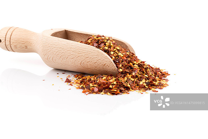 一勺压碎的红辣椒、干辣椒片和辣椒籽，白色背景图片素材