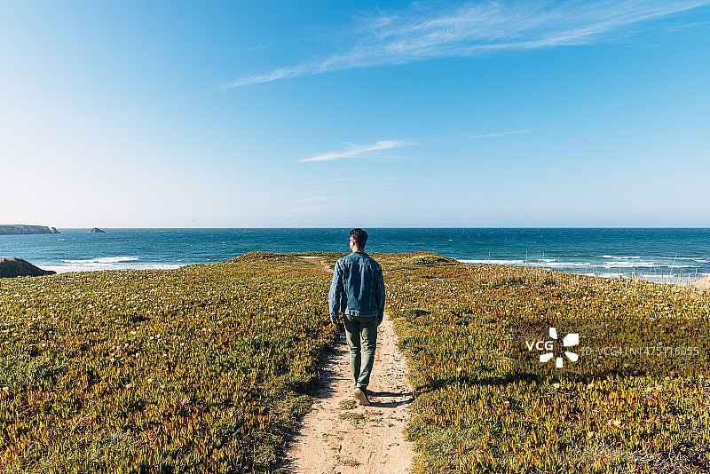 走向葡萄牙海洋的年轻男人的后视图图片素材
