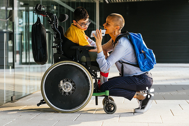 坐轮椅的男孩看母亲手机里的视频图片素材