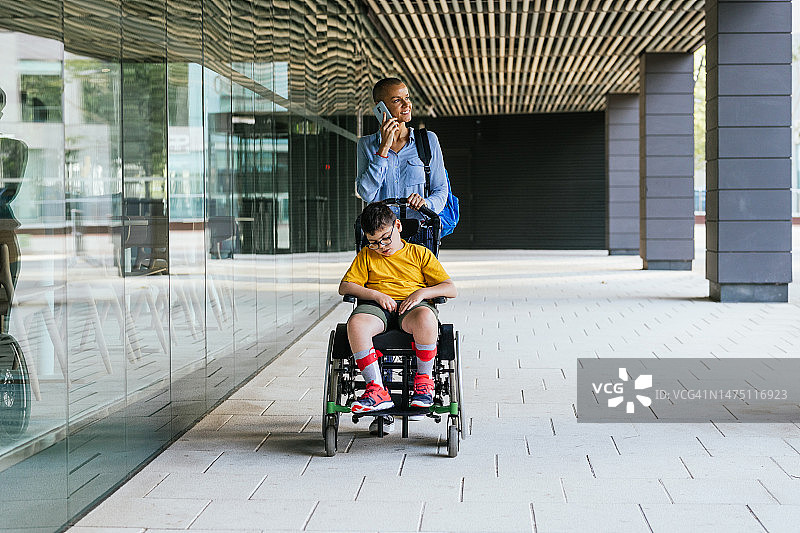 患有行动障碍的儿童在母亲推轮椅时睡着了图片素材