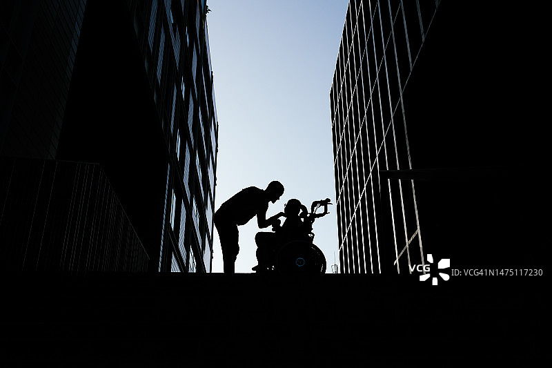 触摸坐在轮椅上的四肢瘫痪儿童脸庞的女人剪影图片素材