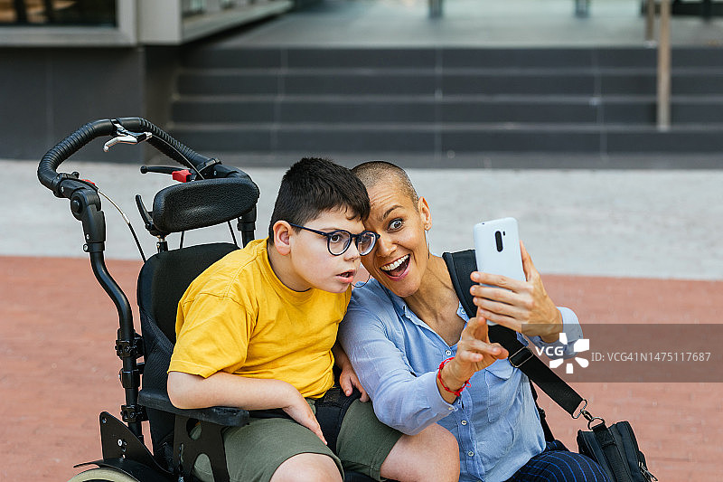 坐在轮椅上的运动障碍儿童与妈妈自拍图片素材
