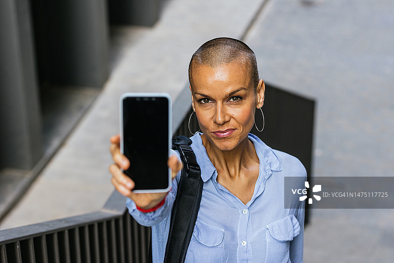 在户外展示带空白屏幕手机的微笑短发女人图片素材