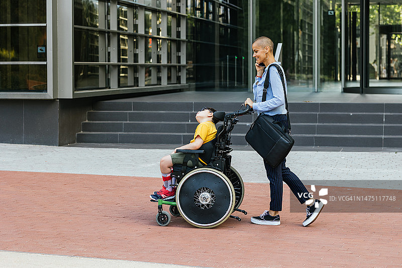 母亲和坐轮椅的儿子在城市里度过阳光明媚的一天图片素材