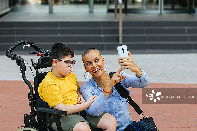 面带微笑，与坐轮椅的儿子自拍的中年母亲图片素材