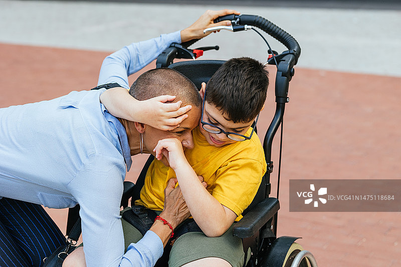 坐在轮椅上的四肢瘫痪儿童拥抱他的母亲图片素材